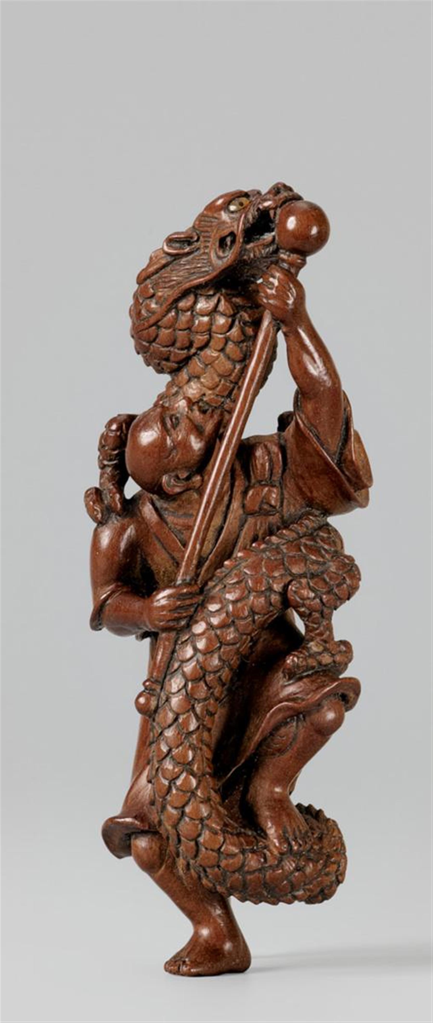 A wood netsuke of a rakan warding off a dragon, by Akihide. Around 1980 - image-1