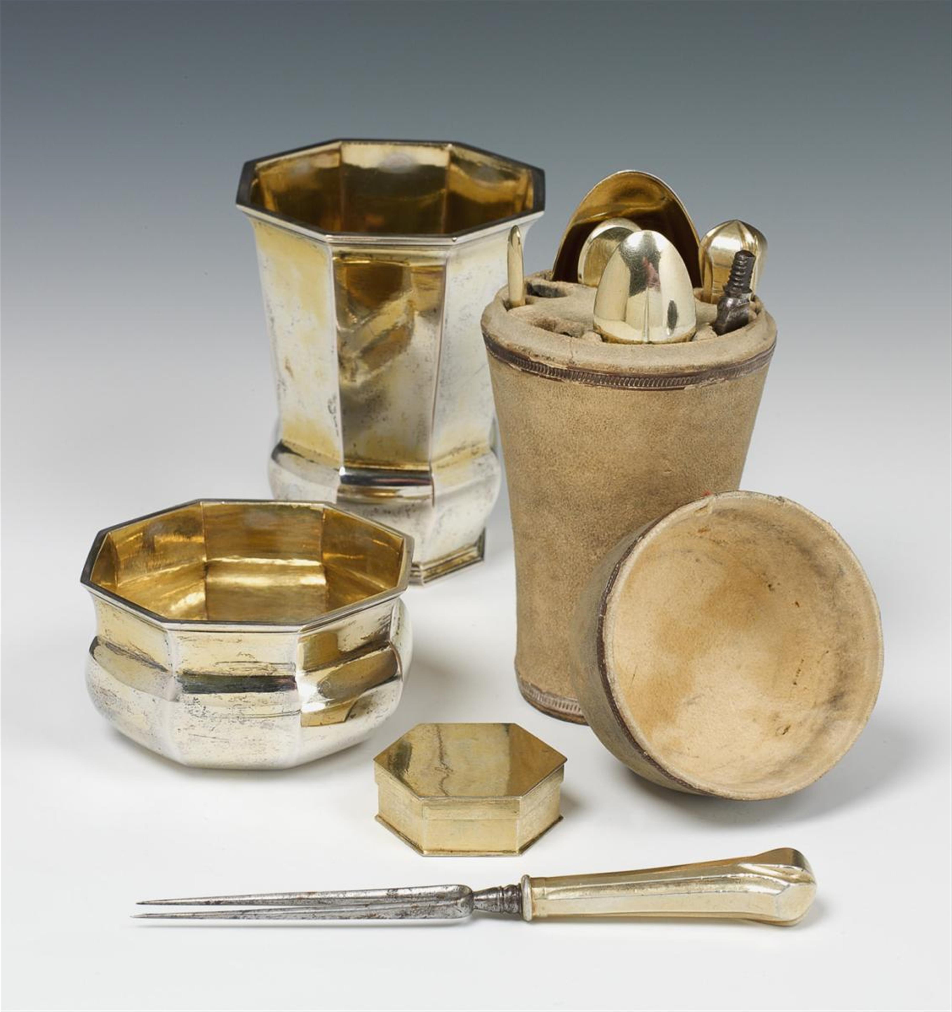 A set of Breslau silver gilt travel cutlery in a beaker. Comprising an octagonal beaker and tumbler containing a leather case fitted with a spice container, folding spoon, screw-mounted fork and knife, coffee spoon, bone marrow spoon and ear cleaning spoo - image-1