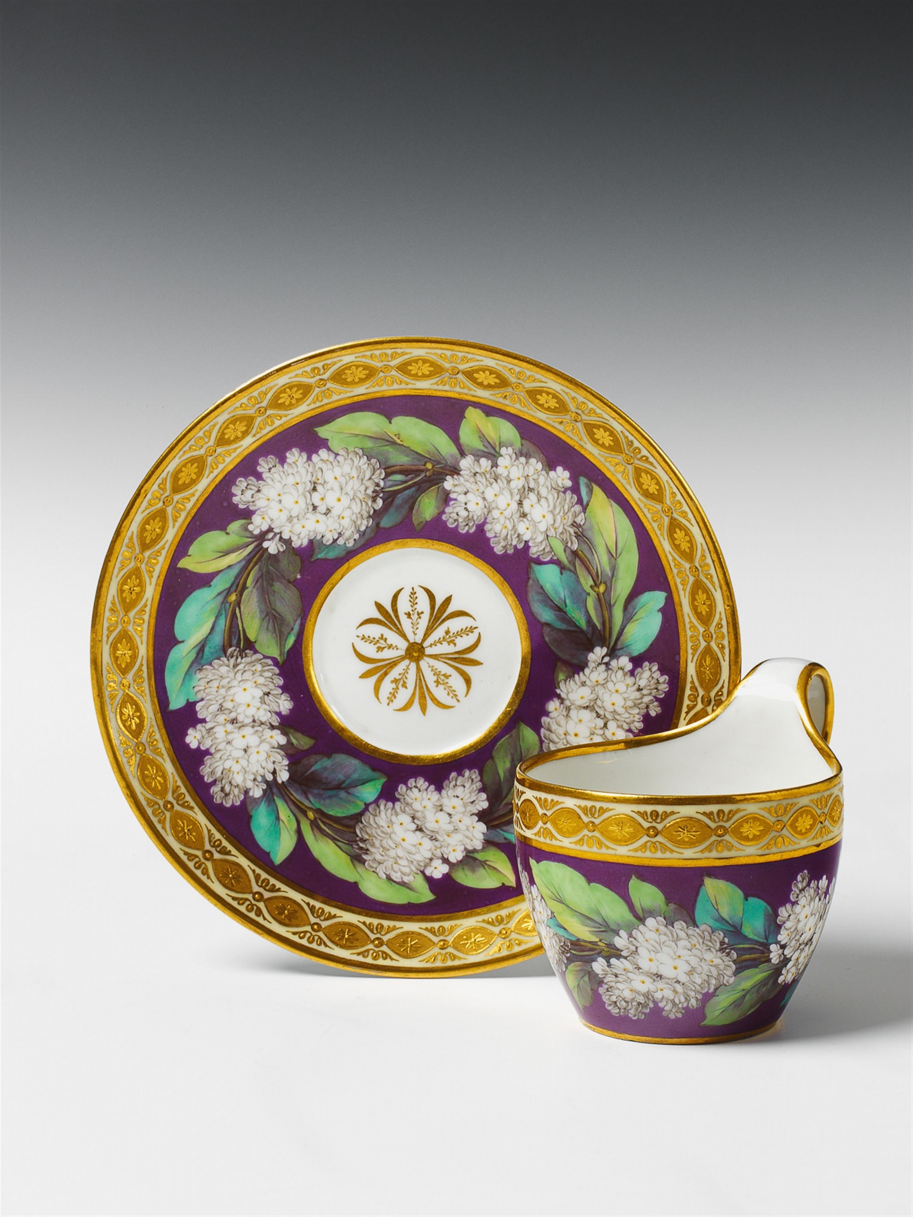 A Berlin KPM porcelain cup and saucer with lilac flower and gilt relief decor. - image-1
