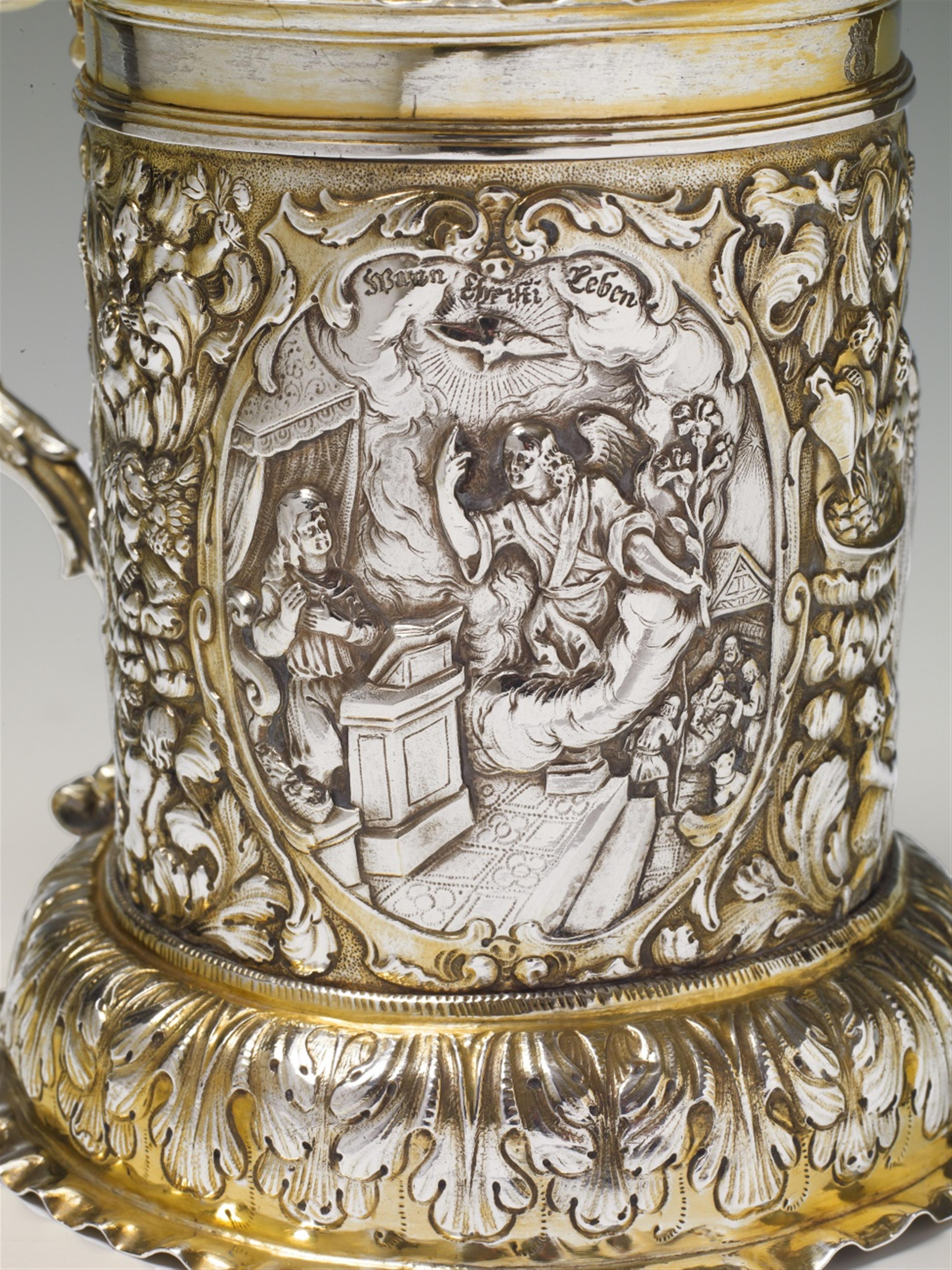 A Nuremberg silver gilt tankard. Of cylindrical form on a bulbous base, the rim moulded and the volute handle decorated with a female herm. The body engraved and embossed with biblical scenes in three oval reserves: 1. The creation of Eve, 2. The annuncia - image-2