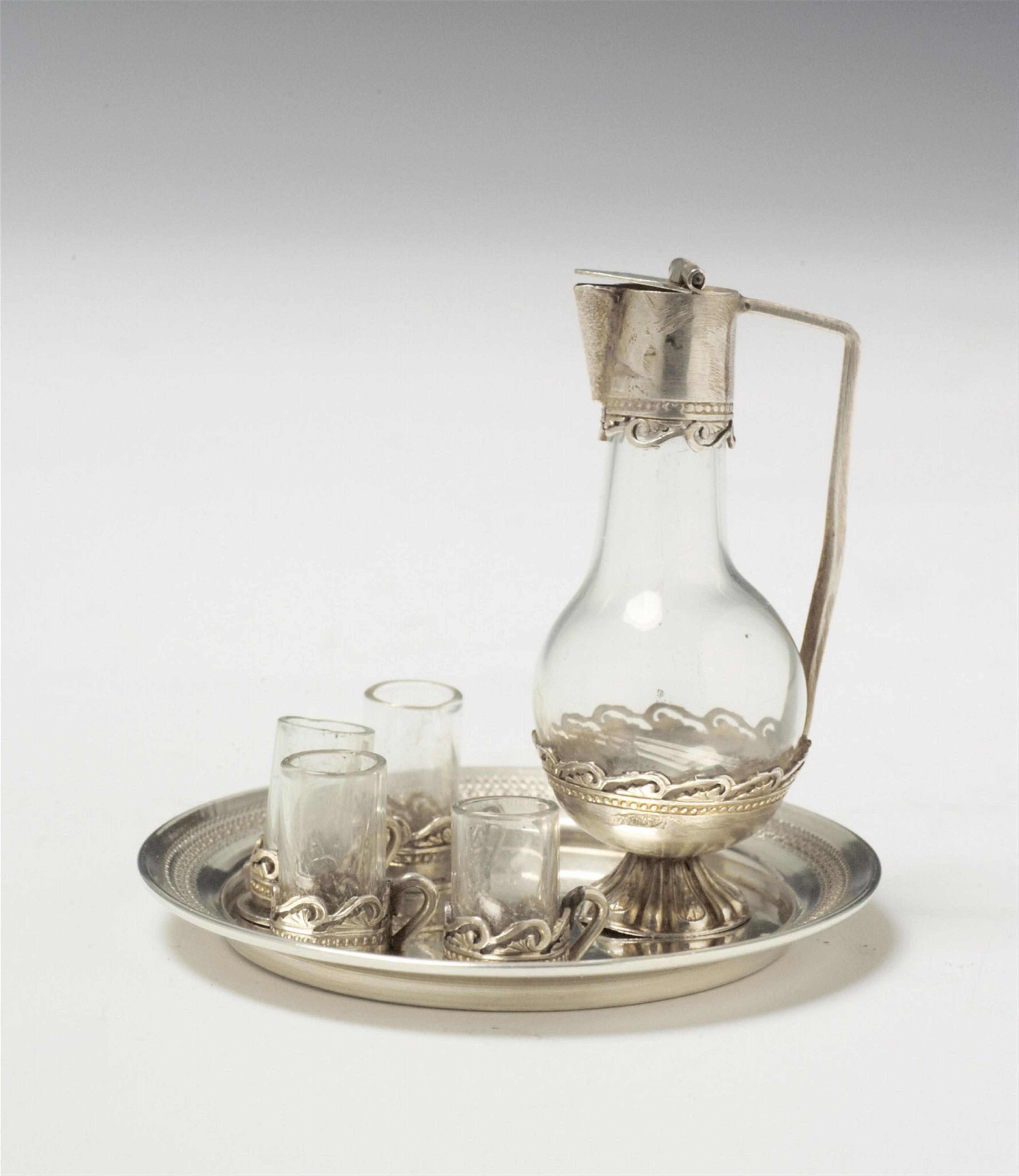 A presumably French miniature liqueur service. Comprising a silver mounted caraffe, four glasses and a tray. An indistinct rhombus shaped mark to the tray, probably French, 19th C. - image-1
