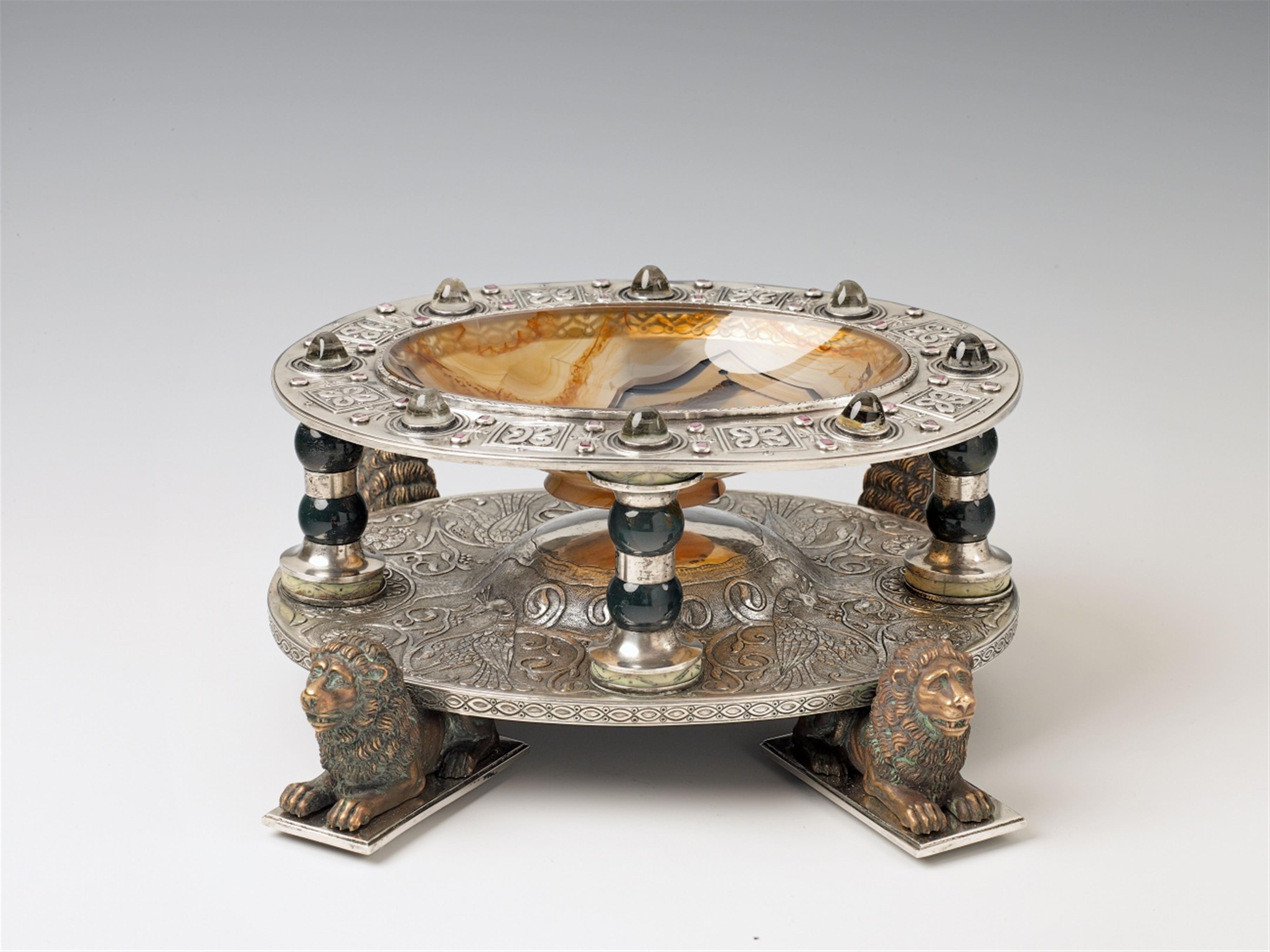 An opulent Aachen silver historicist dish. Mounted on four bronze lions, set with coloured stone and rock crystal cabochons. With an agate dish to the central element, supported by four jasper columns. Marks of Johann Heinrich Hubert Steenaerts, ca. 1860. - image-1