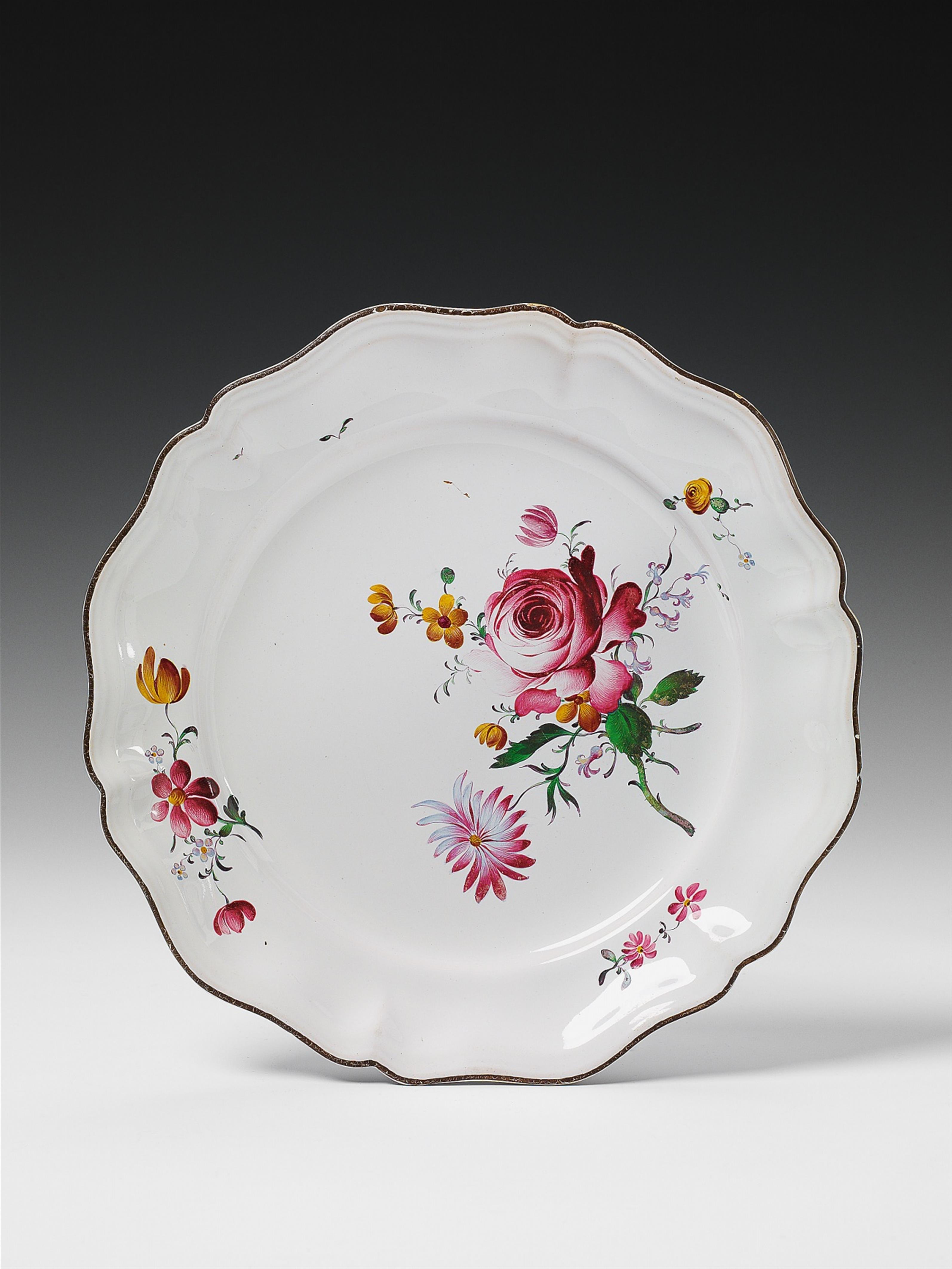 A scalopped Strasbourg faience plate with floral overglaze decor. - image-1