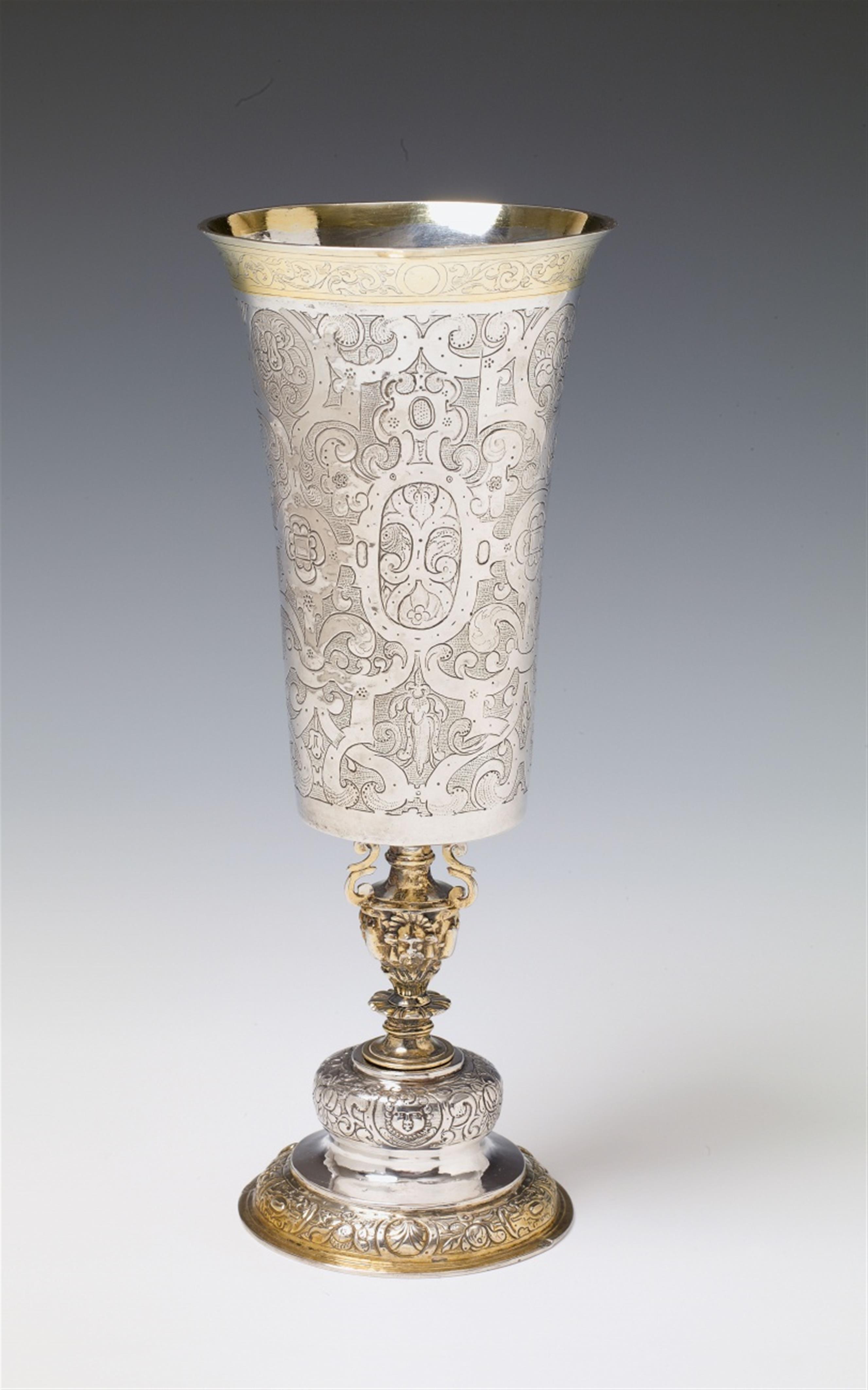 A Frankfurt renaissance silver partially gilt cup. With a round, waisted foot decorated with portrait reliefs in reserves between embossed strapwork and fruit. The cast pommel with four symmetrical mascarons and volutes. The conical cup with floral and sc - image-1