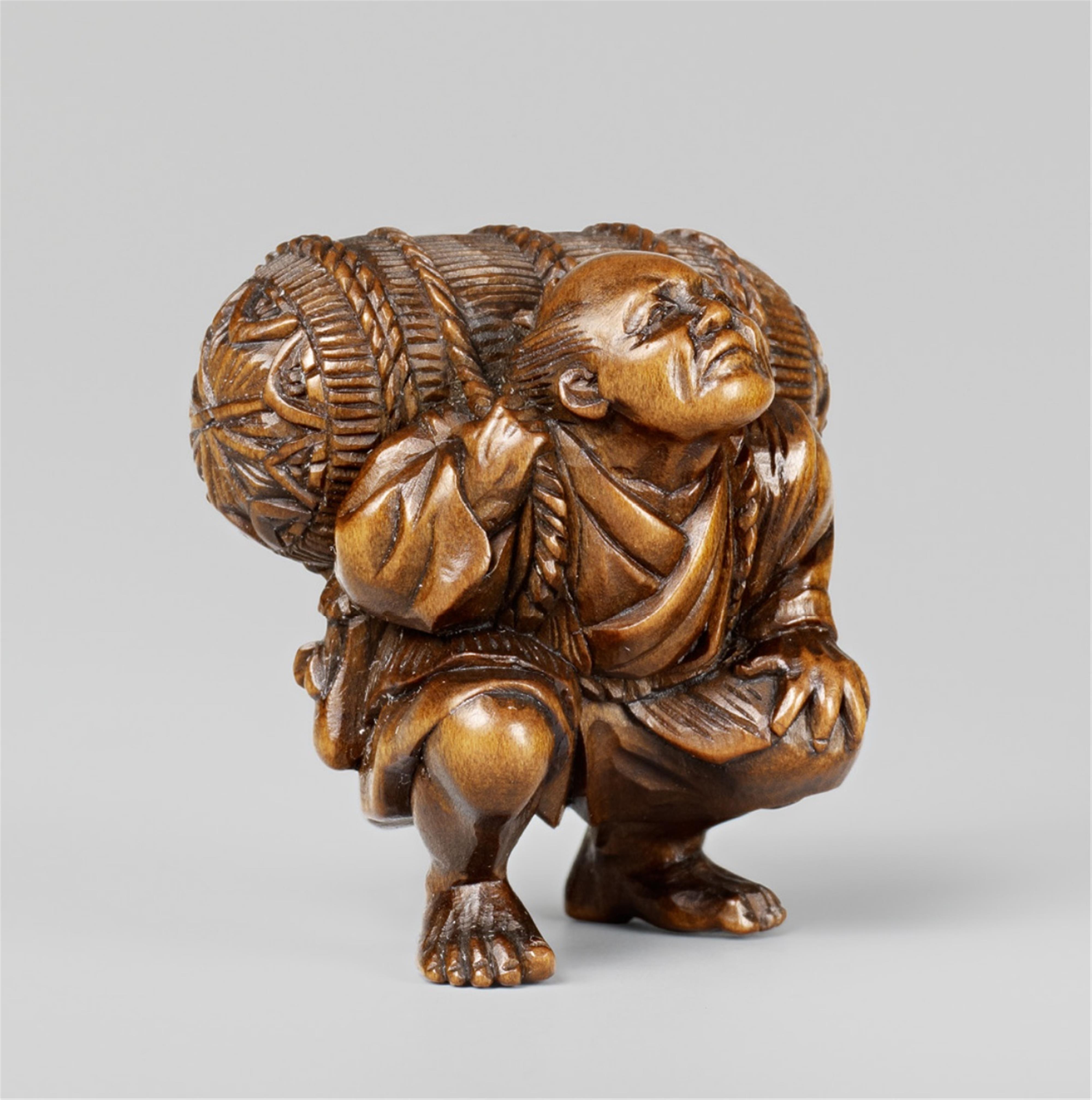 A small boxwood netsuke of a workman with a rice bale, by Hôkei. Late 19th century - image-1