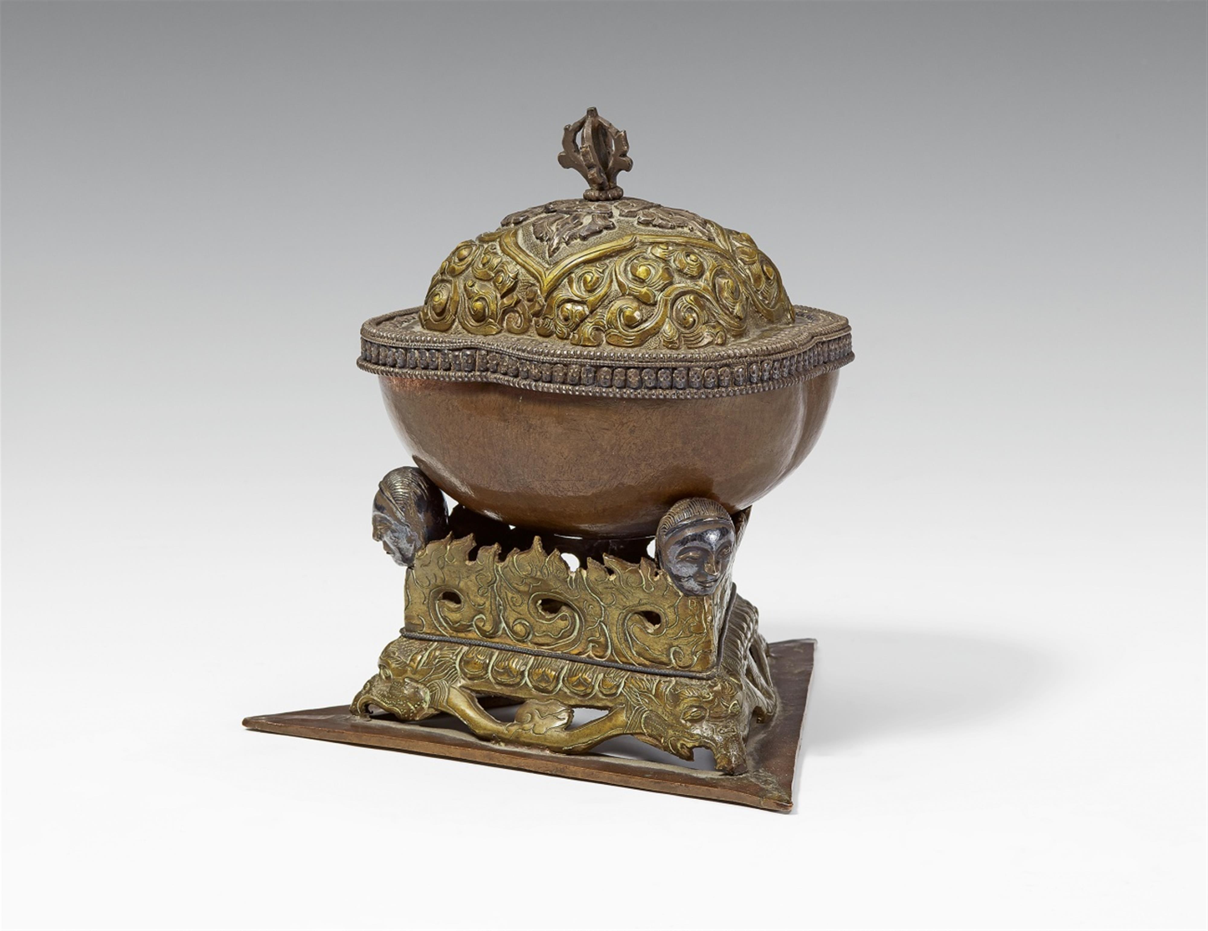 A Tibetan copper kapala with a brass lid and stand with silver details - image-2