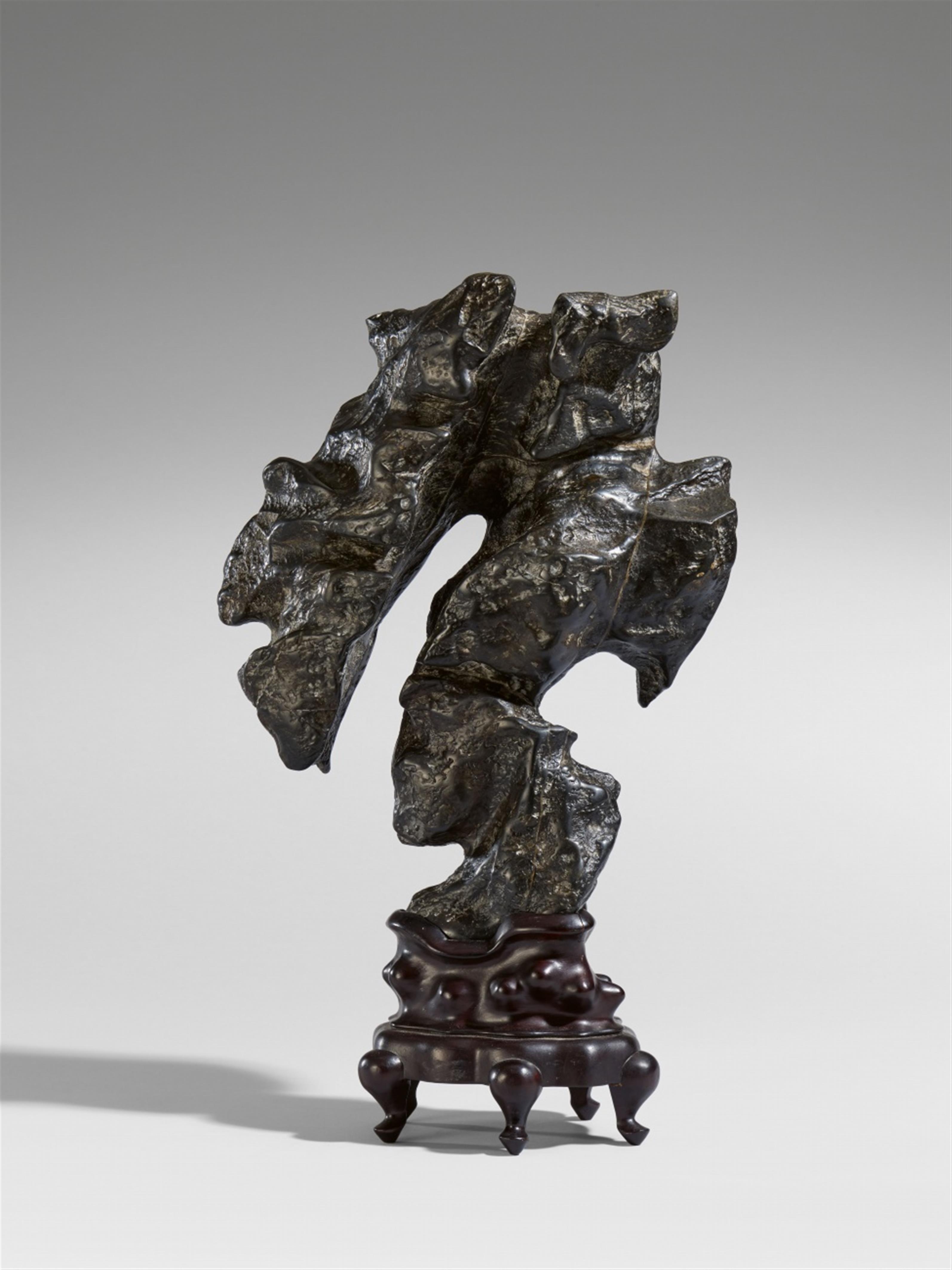 A black bronze 'scholar's rock' on a carved wooden stand - image-1
