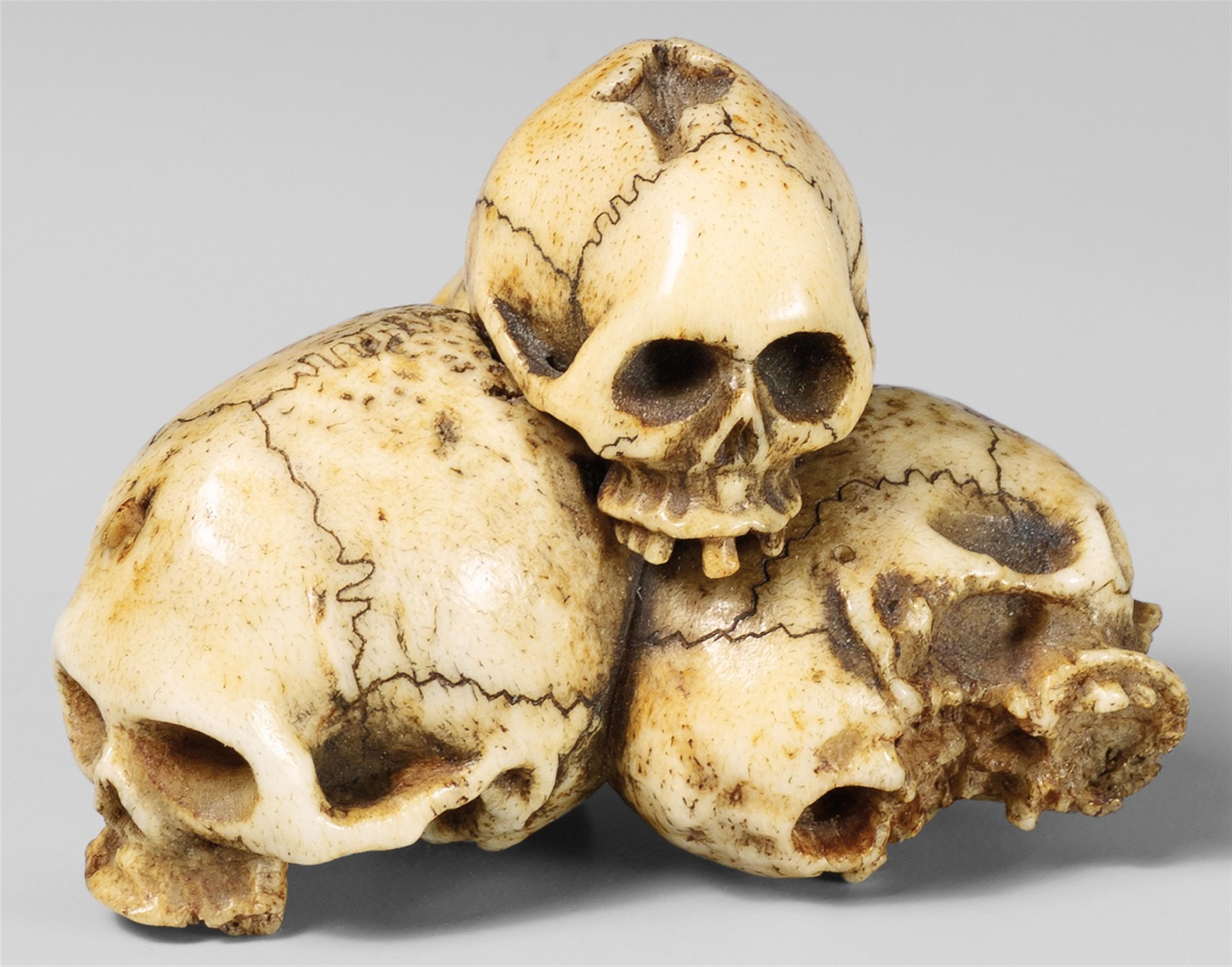 A bone netsuke of a group of four skulls. Late 19th century - image-1