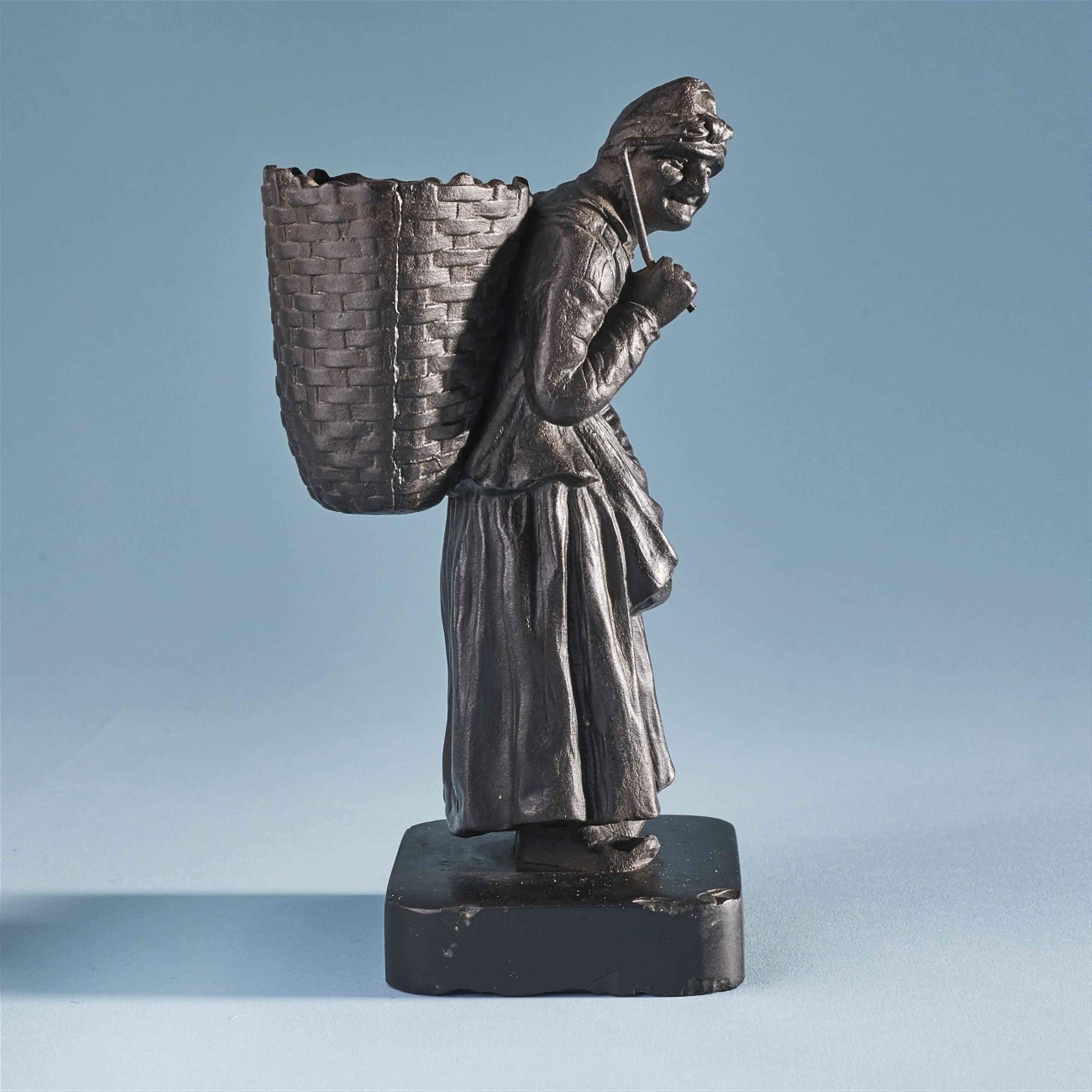 A cast iron model of an old lady with a basket on her back - image-2