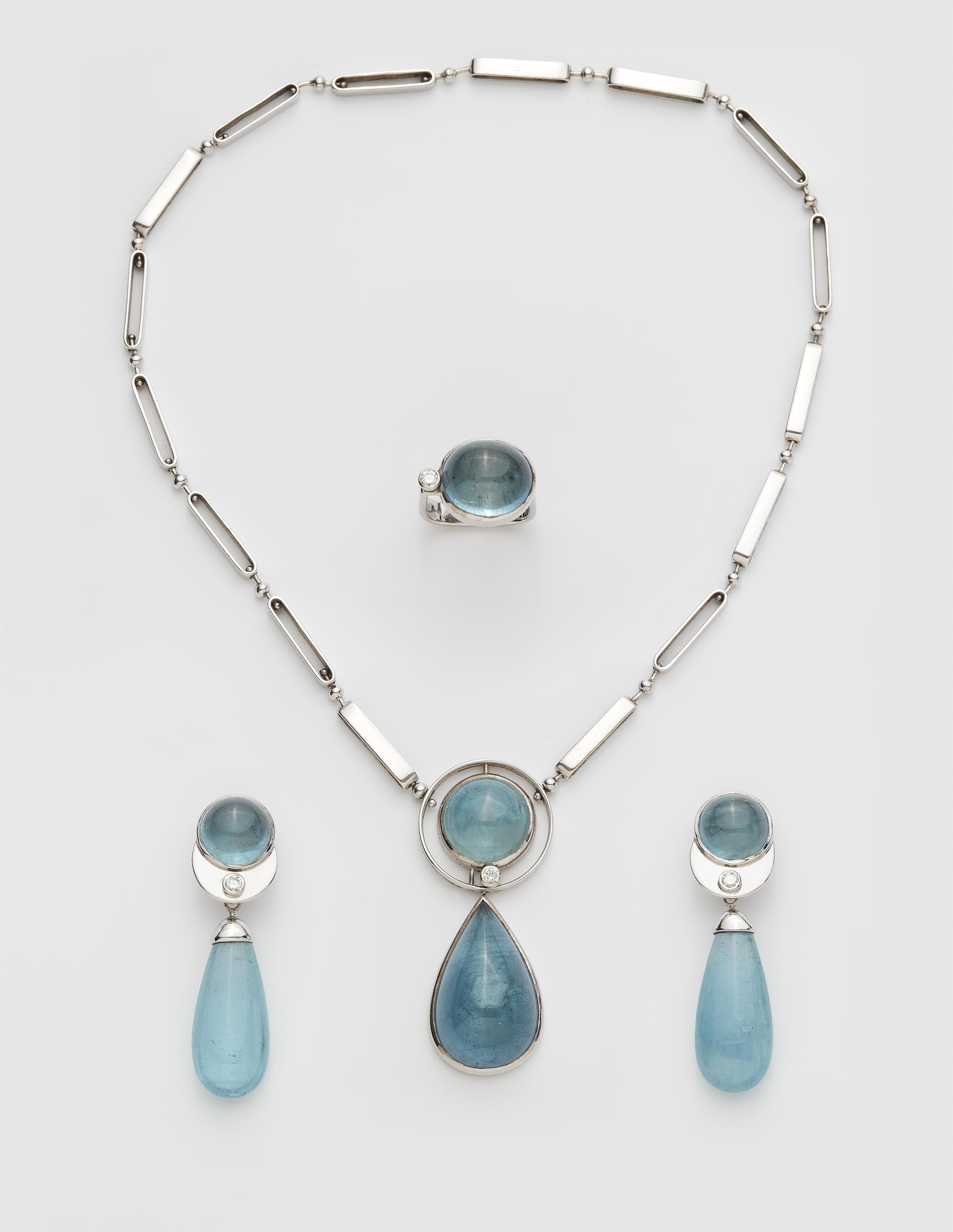 A German 18k white gold diamond and aquamarine cabochon suite comprising a pendant necklace, a pair of earrings and a ring. - image-1