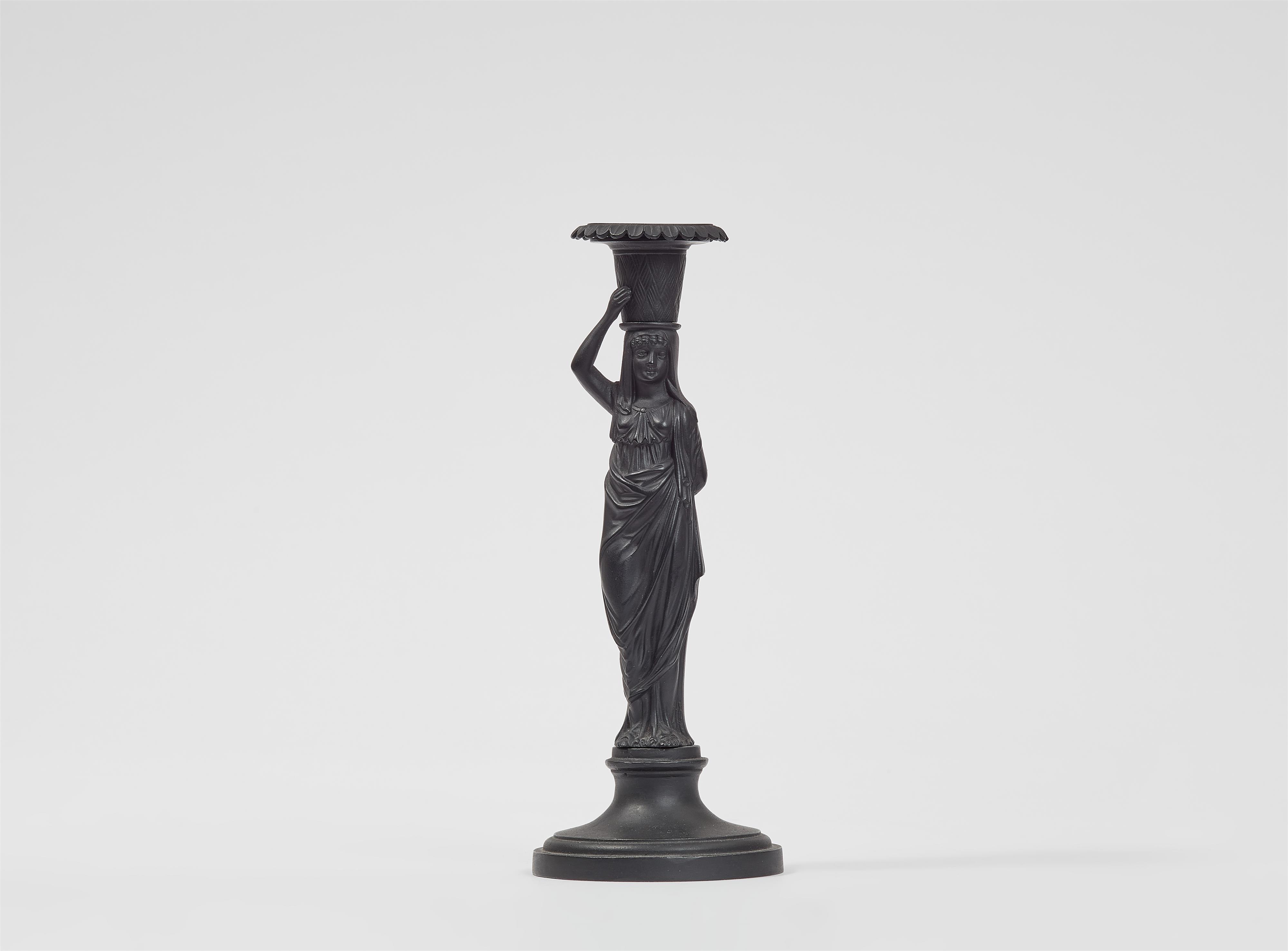 A cast iron candle holder formed as a lady with a basket - image-1