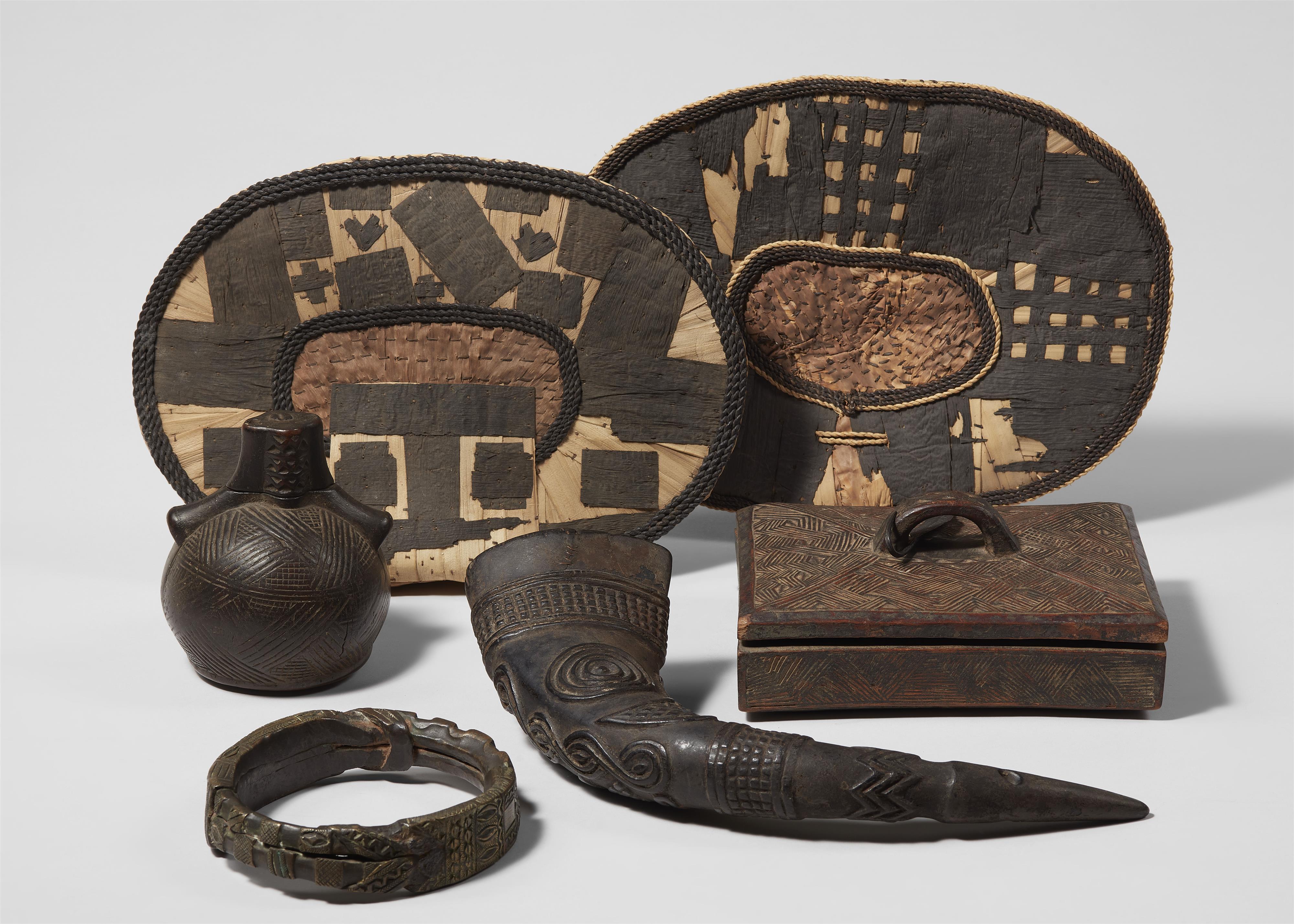 SIX CONGO ARTEFACTS 
Two Mangbetu buttock ornaments, negbe; a Teke brass bracelet; a Kuba carved horn; a Kongo carved powder flask; and a Kuba box and cover - image-1