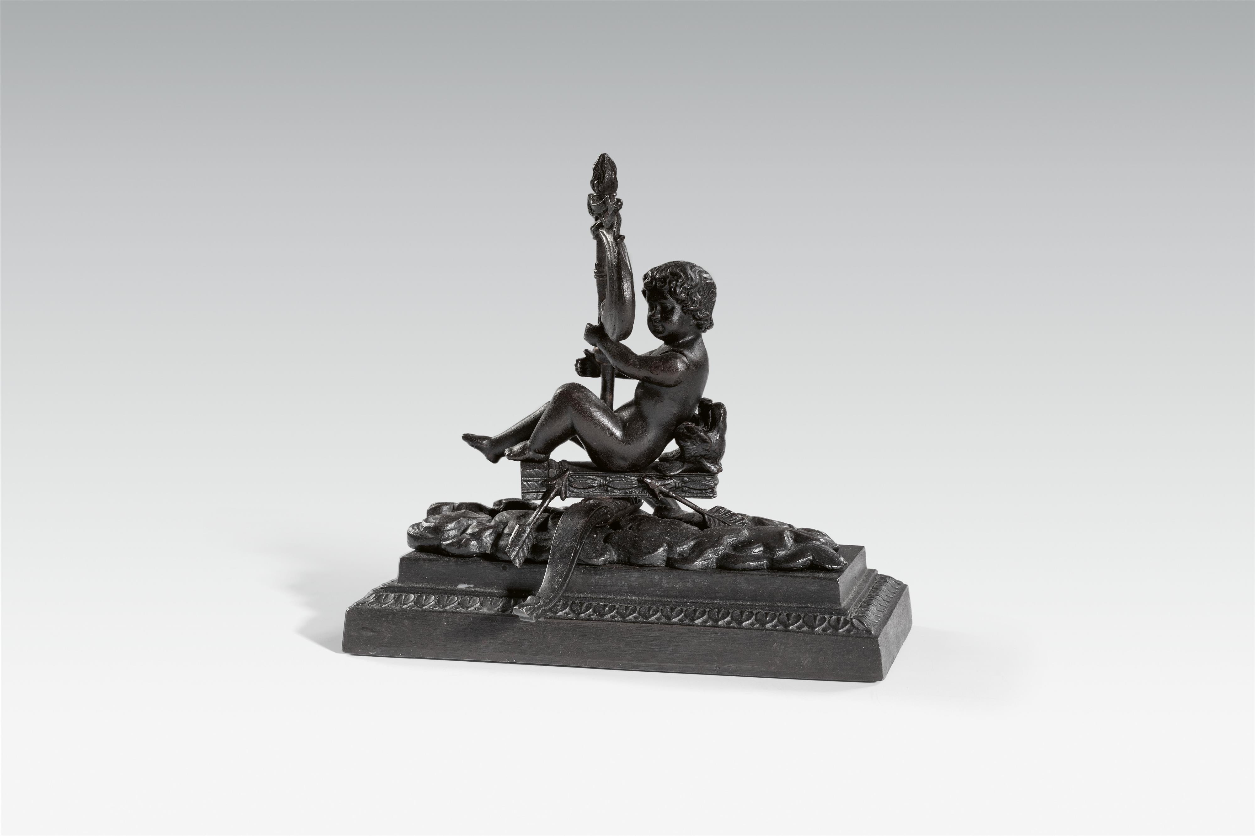 A cast iron paperweight with a figure of Cupid sailing - image-1