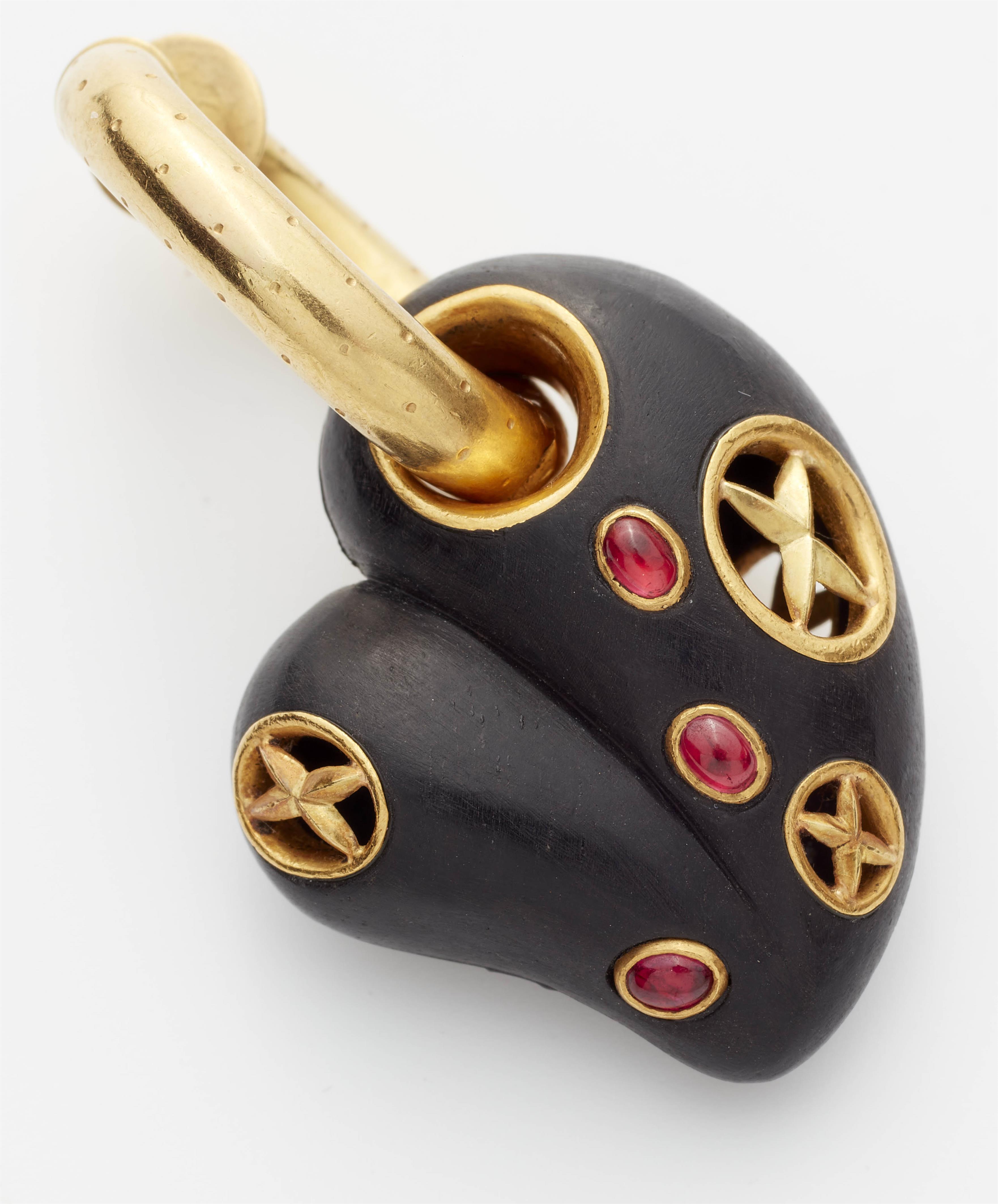 A pair of 18kt gold hoop earrings with ruby set carved ebony heart pendants. - image-3