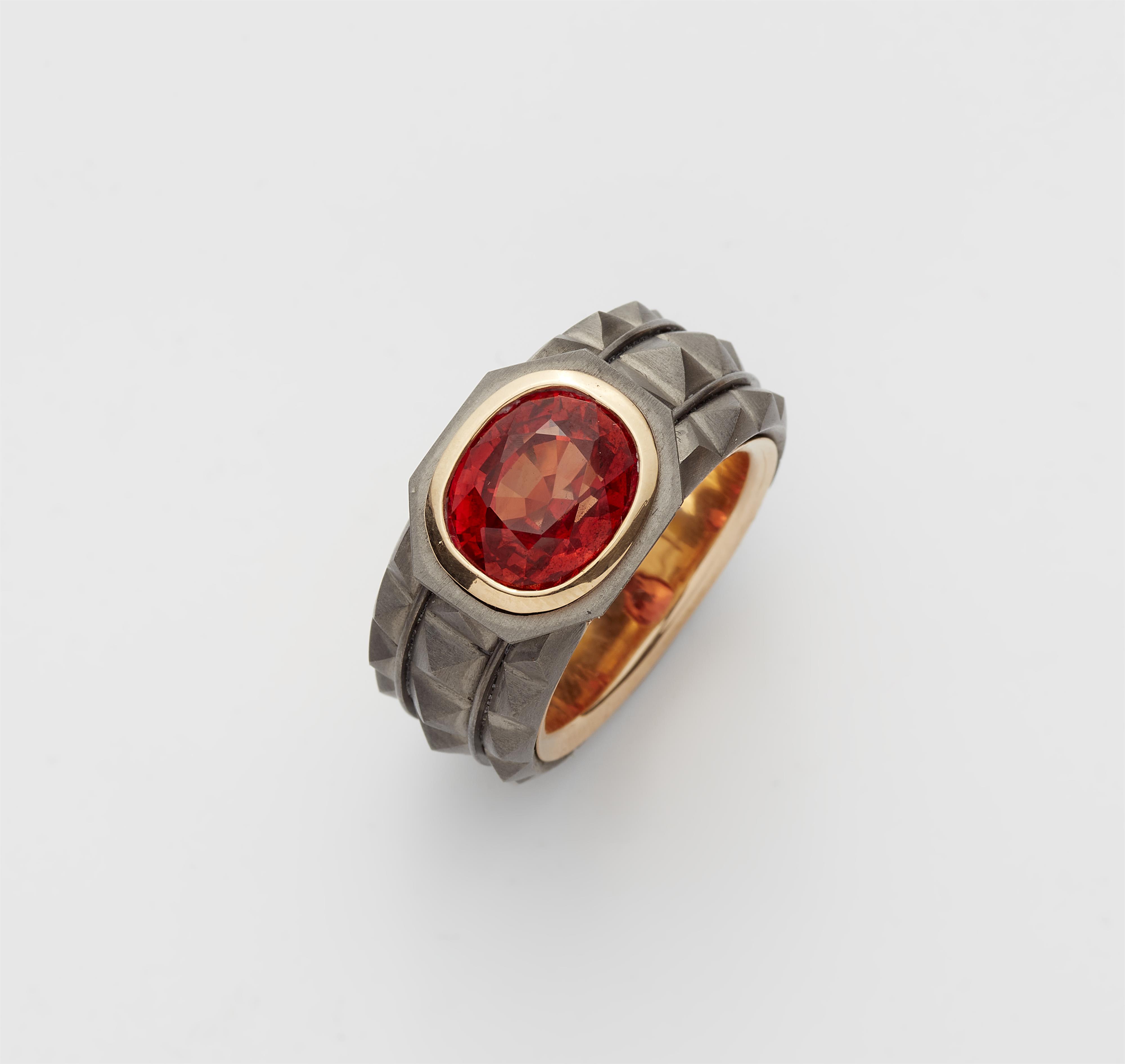 A German 18k gold and forged grey iron band ring with a natural orange coloured sapphire. - image-1