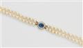 A pearl necklace with a diamond and sapphire clasp - image-1