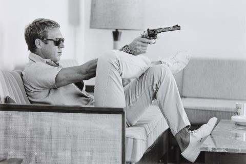 John Dominis - Steve McQueen aims a pistol in his living room, CA