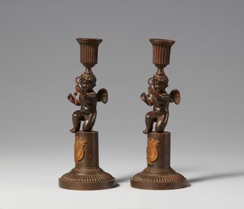  Königliche Eisengießerei Berlin - A pair of cast iron candlesticks with kneeling Cupid figures